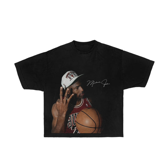 Image description: A graphic tee featuring Michael Jordan in his iconic 3 rings pose, celebrating his third championship win. The design pays homage to the basketball legend and is a comfortable choice for fans looking to commemorate this iconic moment in sports history.